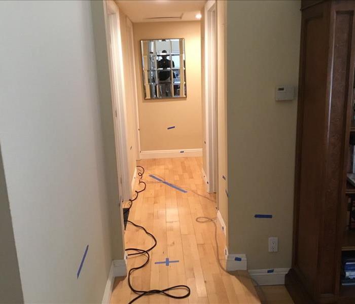hallway with blue tape strips on wall and wood floors