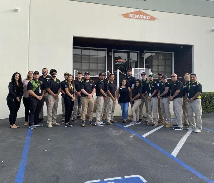 group photo of SERVPRO team in parking lot with tan building in the background 