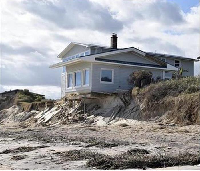 House on the beach with storm damage. Large area of sand. 