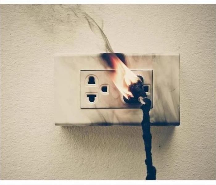 Fire started from an outlet in the wall with a black corn plugged in 